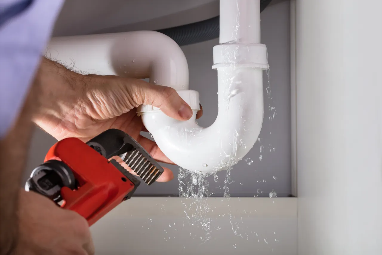 Professional plumber repairing a leaking sink drain pipe with a wrench in New York