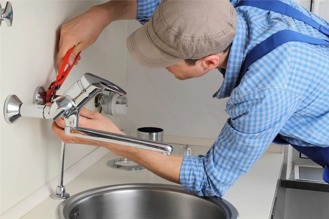 Professional plumber installing a kitchen faucet over a sink in New York