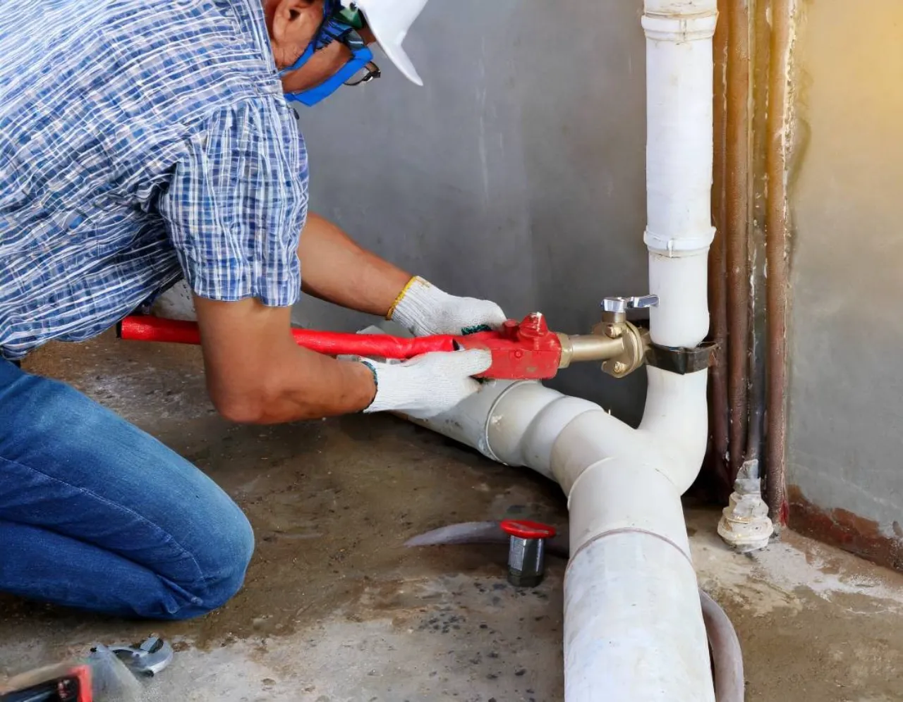 Professional plumber repairing a leaking pipe connection with a pipe wrench in a New York property